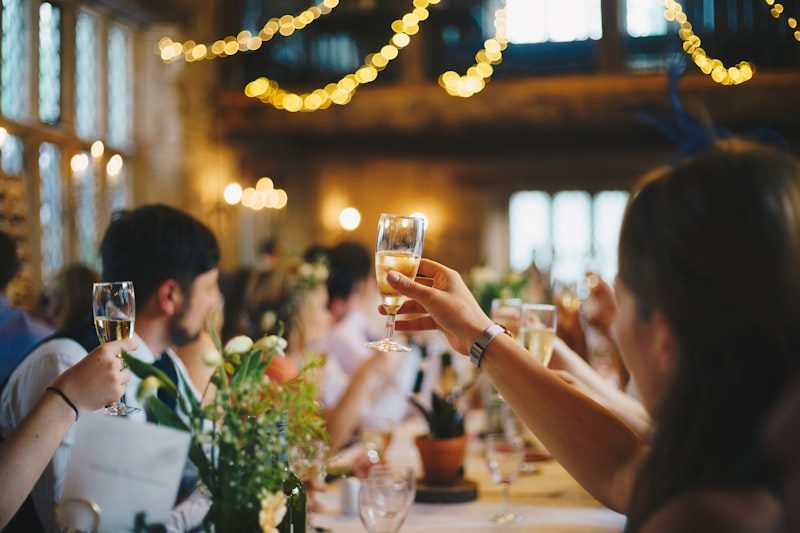 Guests raising glasses around a table under string lights