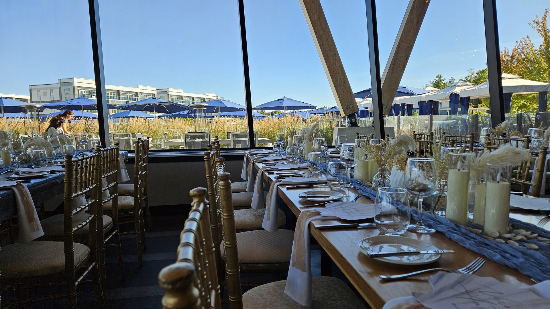 Reception tables with gold chairs, candles, pampas grass, and pale blue runners