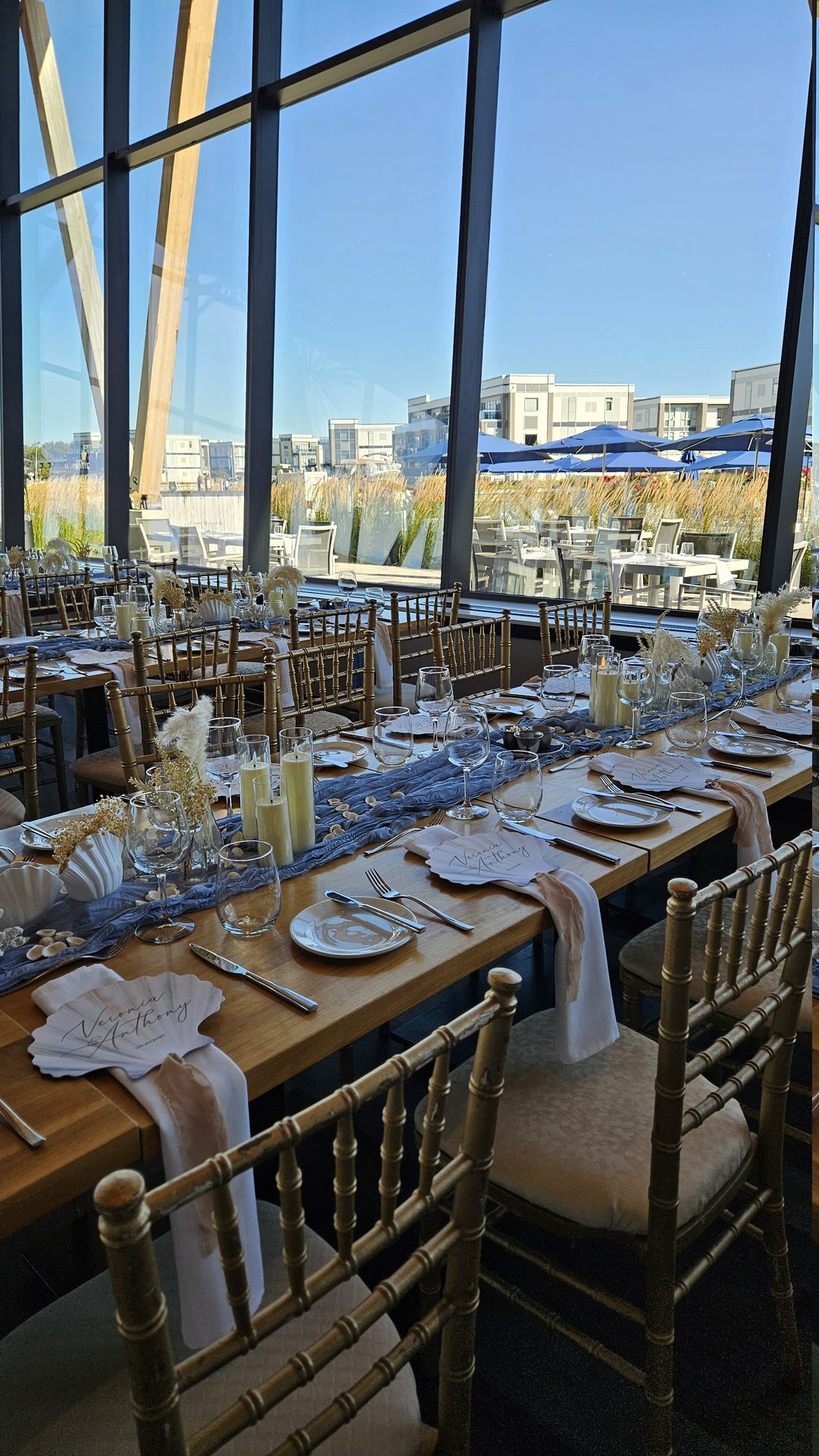 Table detail with candles, pale blue runner, shell place cards, and textured florals
